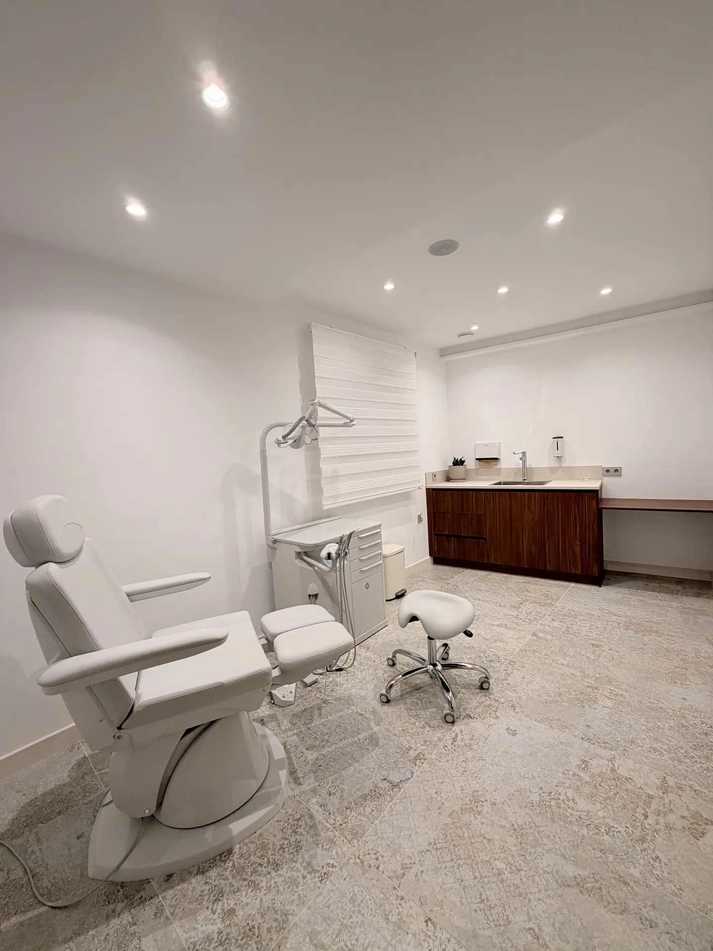 Gabinete de podología con sillón de tratamiento, taburete y encimera de trabajo con lavabo